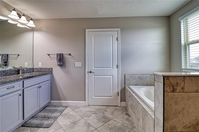 full bathroom featuring tile patterned flooring, a garden tub, a textured ceiling, and vanity