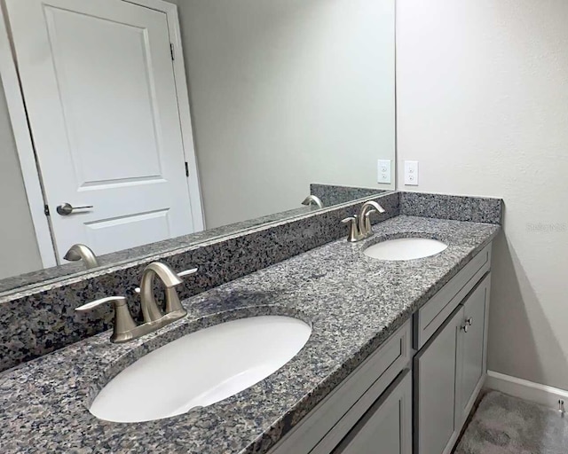 bathroom with a sink, baseboards, and double vanity