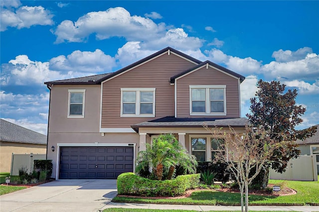 traditional home featuring driveway, a garage, fence, and stucco siding