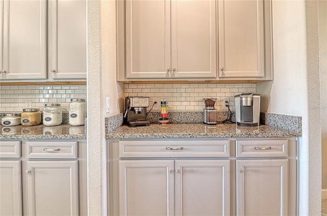 kitchen featuring tasteful backsplash, white cabinetry, and light stone counters