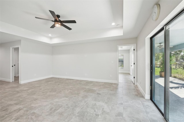 spare room with ceiling fan and a tray ceiling