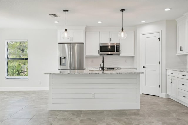 kitchen featuring white cabinets, stainless steel appliances, light stone counters, and a center island with sink