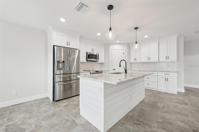 kitchen with light stone countertops, stainless steel appliances, a kitchen island with sink, sink, and white cabinetry