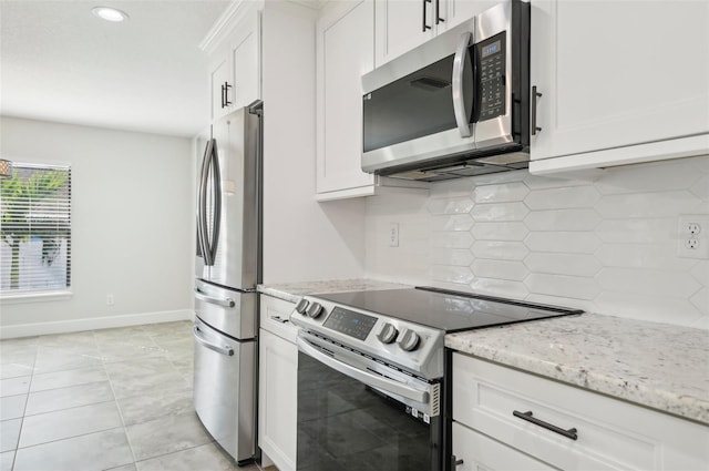 kitchen featuring decorative backsplash, light stone countertops, light tile patterned flooring, white cabinetry, and stainless steel appliances