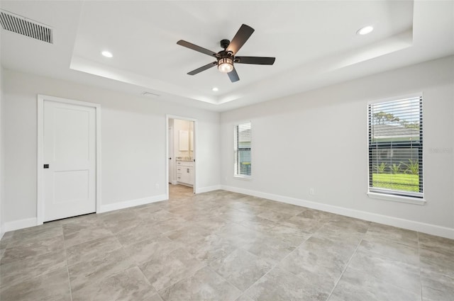 unfurnished bedroom featuring ceiling fan, connected bathroom, and a tray ceiling