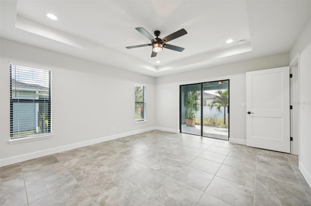 unfurnished room with ceiling fan and a raised ceiling