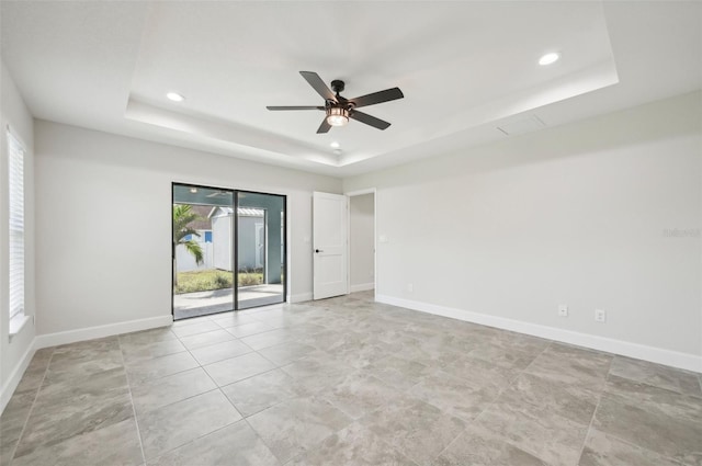 empty room featuring ceiling fan and a tray ceiling