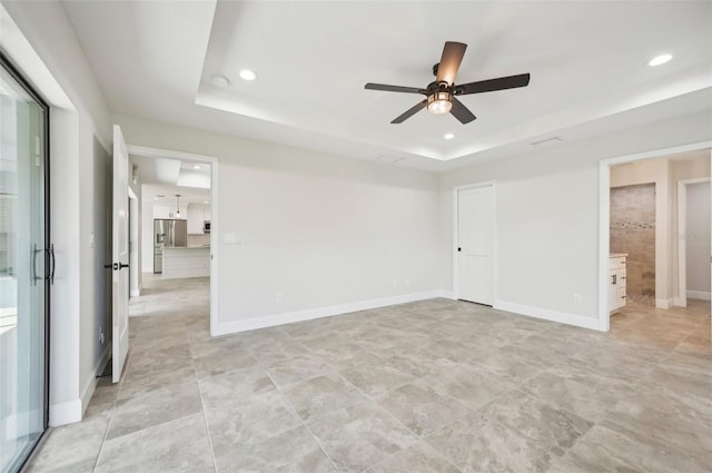 empty room featuring a raised ceiling and ceiling fan