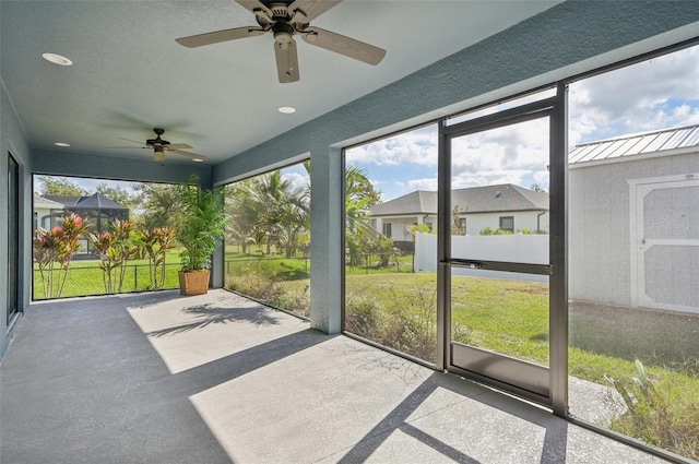 unfurnished sunroom featuring ceiling fan