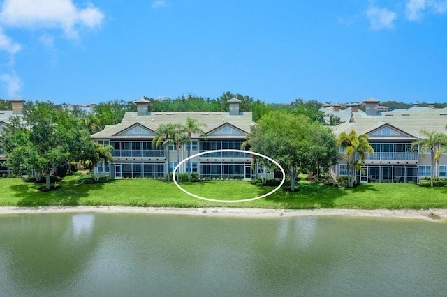 back of property with a lawn and a water view