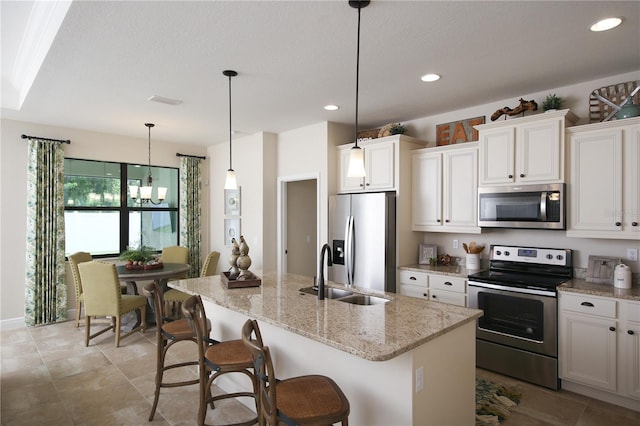 kitchen with white cabinets, stainless steel appliances, sink, and an island with sink