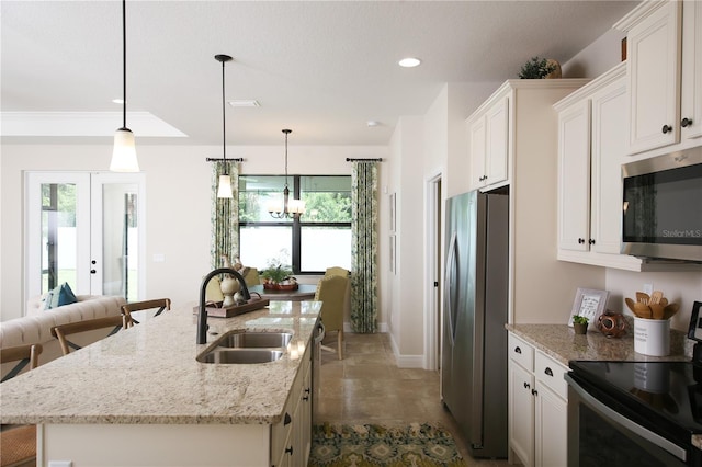 kitchen featuring appliances with stainless steel finishes, decorative light fixtures, sink, and an island with sink