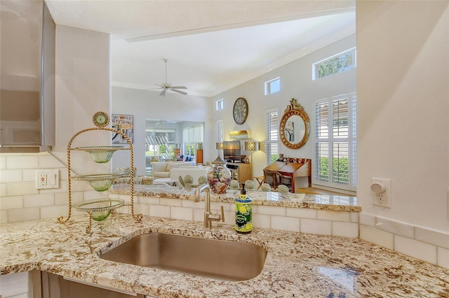 kitchen with light stone countertops, ceiling fan, plenty of natural light, and a sink