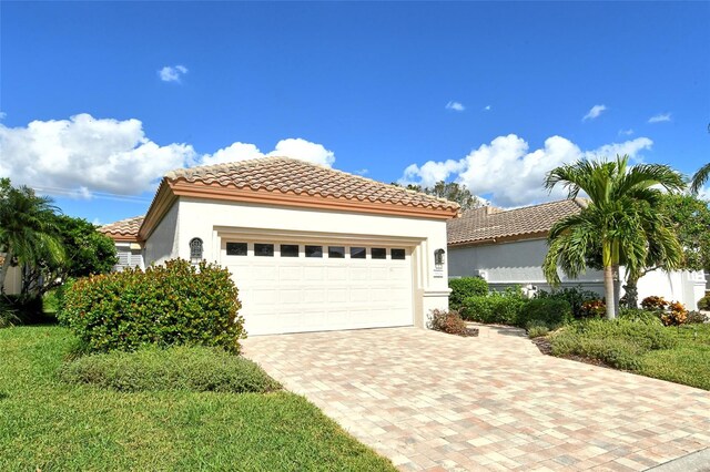 mediterranean / spanish-style home featuring stucco siding, a garage, driveway, and a tile roof