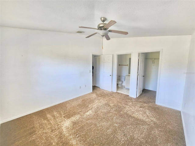 unfurnished bedroom with light carpet, ceiling fan, connected bathroom, and vaulted ceiling