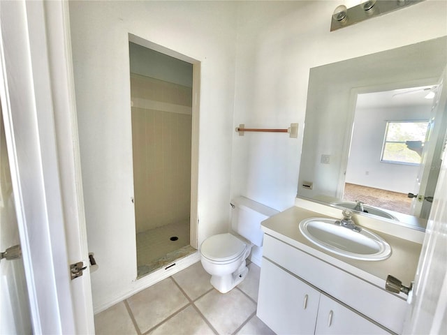 bathroom with vanity, toilet, tile patterned floors, and tiled shower