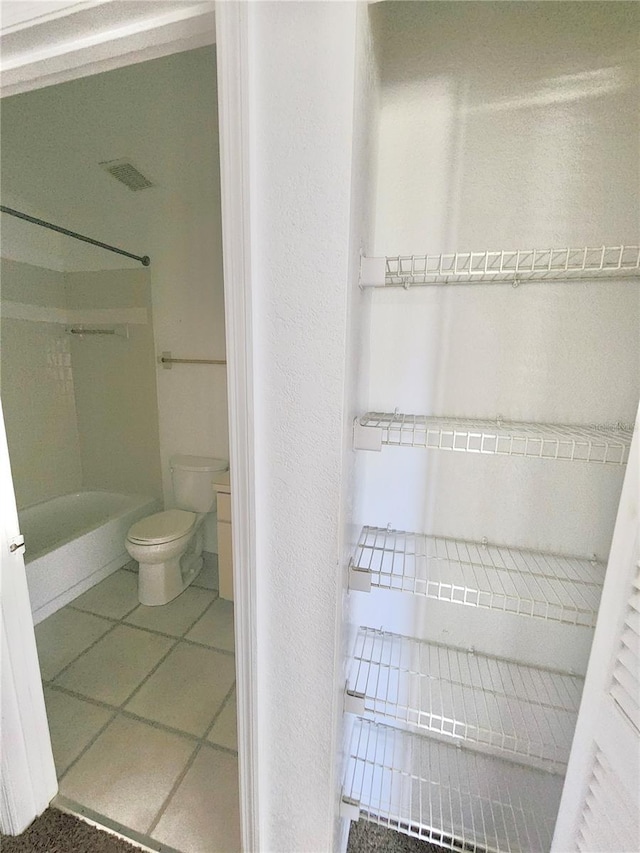 bathroom featuring tile patterned floors, toilet, and walk in shower