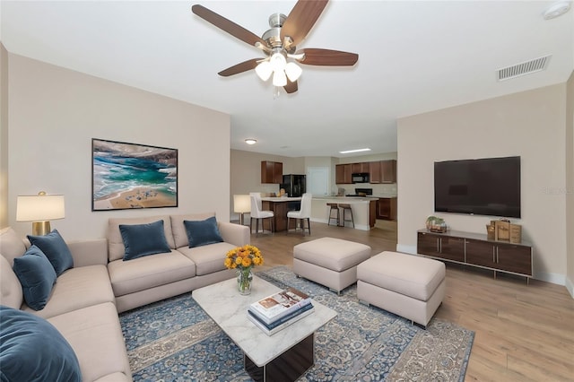 living room featuring ceiling fan and light wood-type flooring