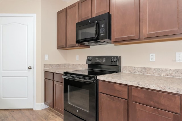 kitchen with black appliances and light hardwood / wood-style flooring