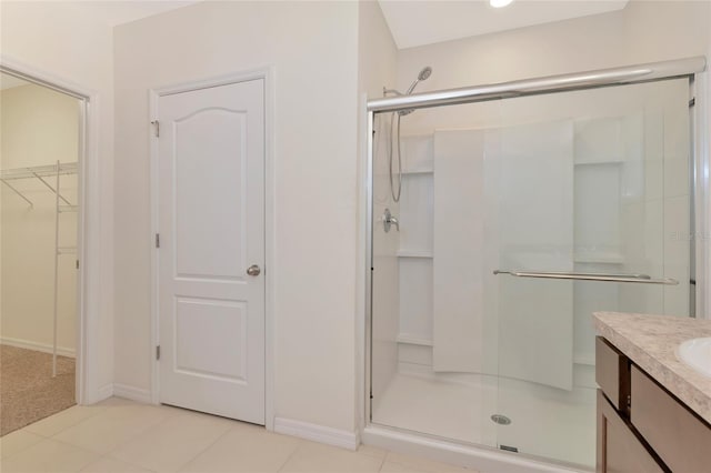 bathroom featuring a shower with shower door, vanity, and tile patterned floors