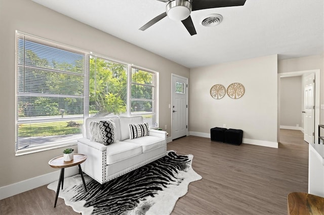 living room featuring dark wood-type flooring and ceiling fan