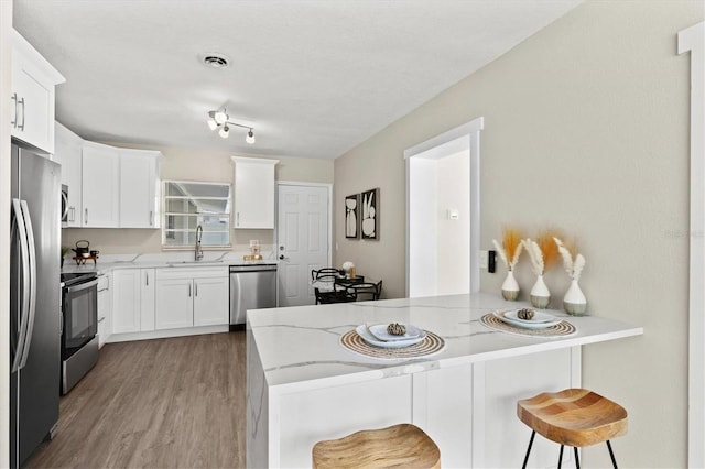 kitchen featuring a breakfast bar area, white cabinets, kitchen peninsula, and stainless steel appliances