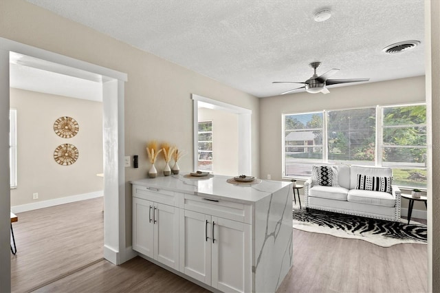 kitchen with white cabinetry, a textured ceiling, light wood-type flooring, and ceiling fan