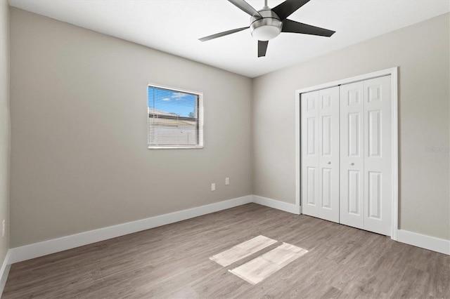 unfurnished bedroom with ceiling fan, baseboards, wood finished floors, and a closet