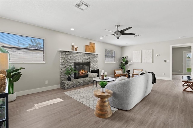 living room with ceiling fan, light hardwood / wood-style flooring, and a fireplace