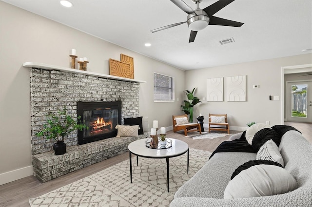 living room featuring a fireplace, hardwood / wood-style flooring, and ceiling fan