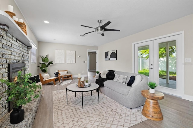 living room with light hardwood / wood-style floors, french doors, a fireplace, and ceiling fan