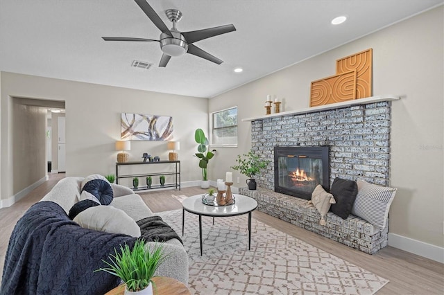 living room featuring ceiling fan, a brick fireplace, and hardwood / wood-style floors