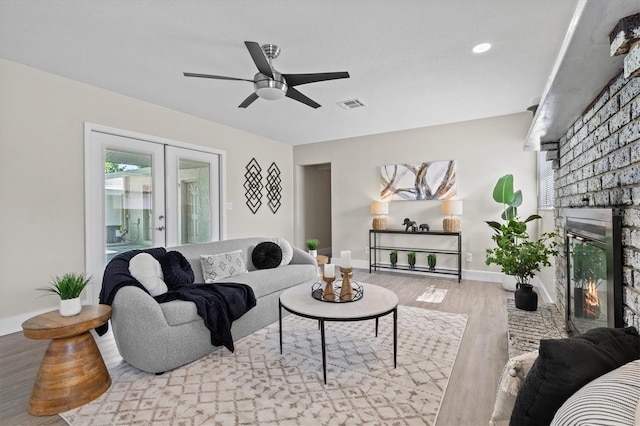 living area featuring baseboards, visible vents, a ceiling fan, wood finished floors, and a fireplace