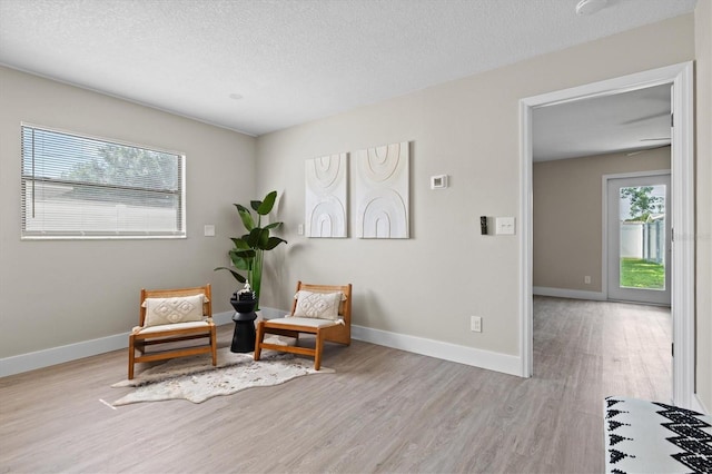 sitting room featuring light hardwood / wood-style floors, a textured ceiling, and a wealth of natural light