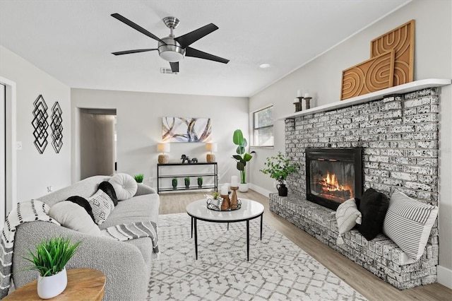 living room featuring hardwood / wood-style floors, ceiling fan, and a brick fireplace