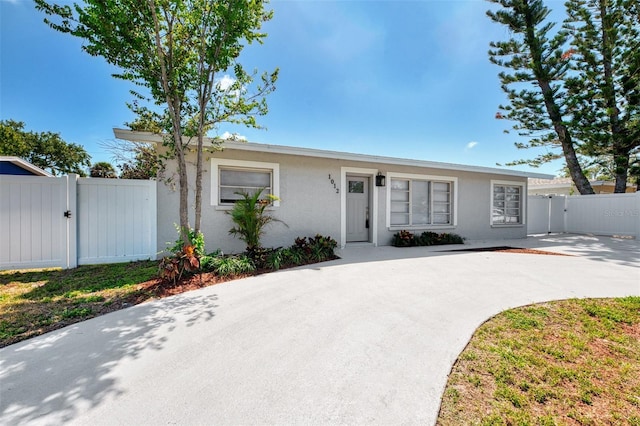 ranch-style home featuring stucco siding, fence, and a gate