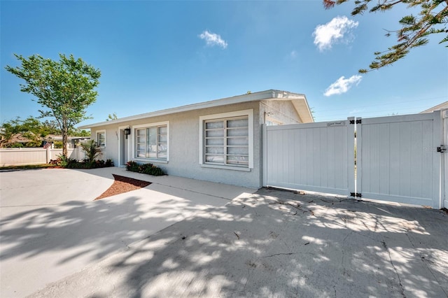 view of front of property with stucco siding, fence, and a gate