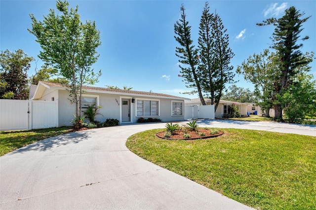 single story home featuring a front yard, stucco siding, a gate, and curved driveway