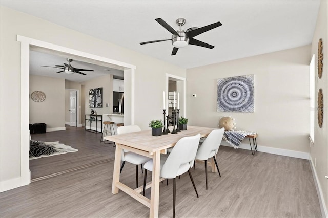 dining space with light wood-style flooring, ceiling fan, and baseboards