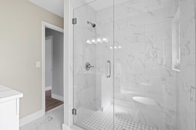 full bathroom with marble finish floor, a marble finish shower, and baseboards