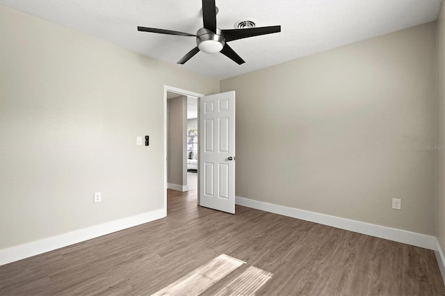 spare room featuring wood finished floors, baseboards, and a ceiling fan