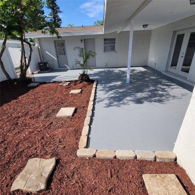 view of yard featuring central AC unit, french doors, and fence