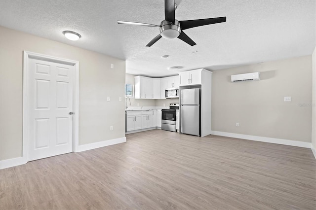 unfurnished living room featuring light wood-type flooring, a ceiling fan, baseboards, and a wall mounted air conditioner