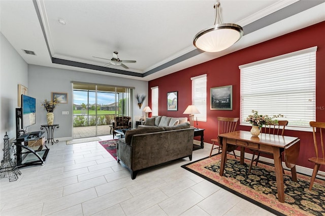 living room with crown molding, a tray ceiling, and ceiling fan