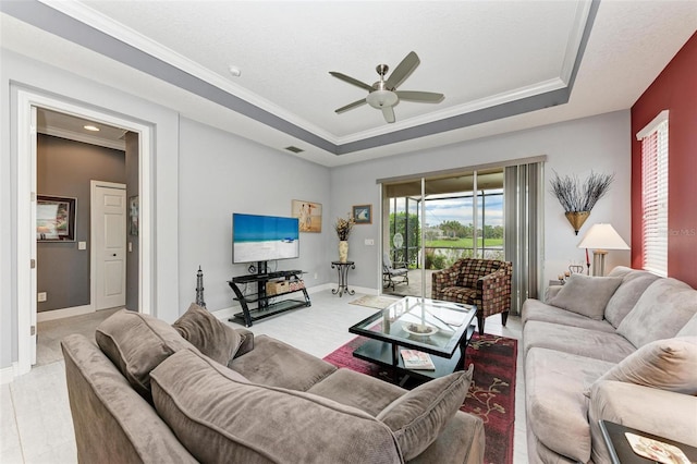 living room featuring ceiling fan, crown molding, and a tray ceiling