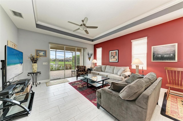 living room featuring ornamental molding, a tray ceiling, and ceiling fan