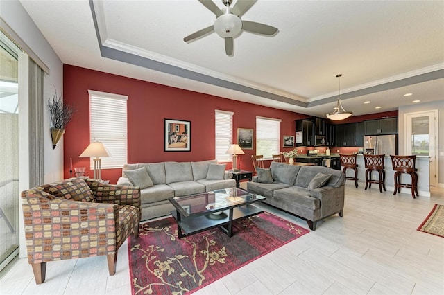 living room featuring ceiling fan, a raised ceiling, and crown molding