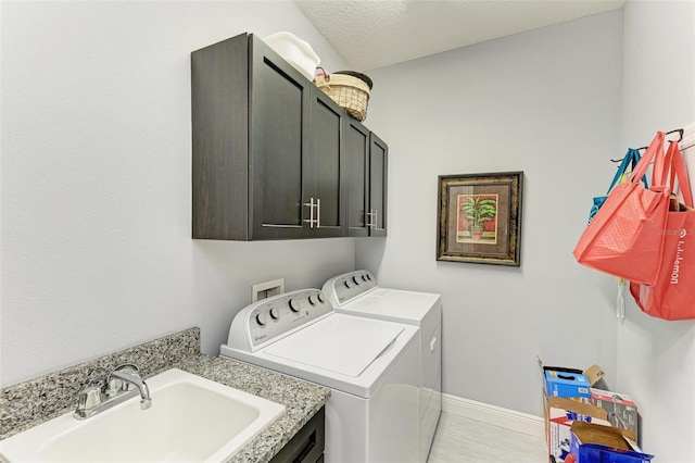 clothes washing area with cabinets, independent washer and dryer, a textured ceiling, and sink