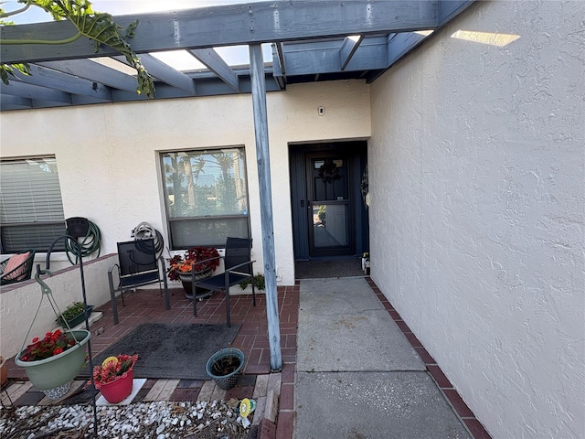 doorway to property with stucco siding and a pergola