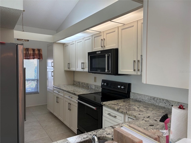 kitchen featuring light stone counters, lofted ceiling, black appliances, and light tile patterned floors